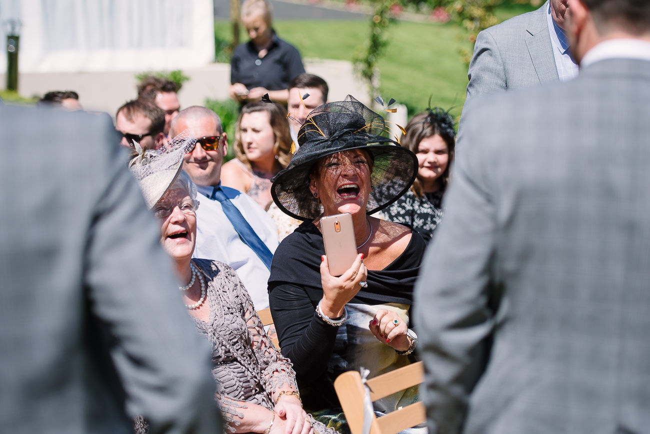 Wedding guest with black hat laughing 