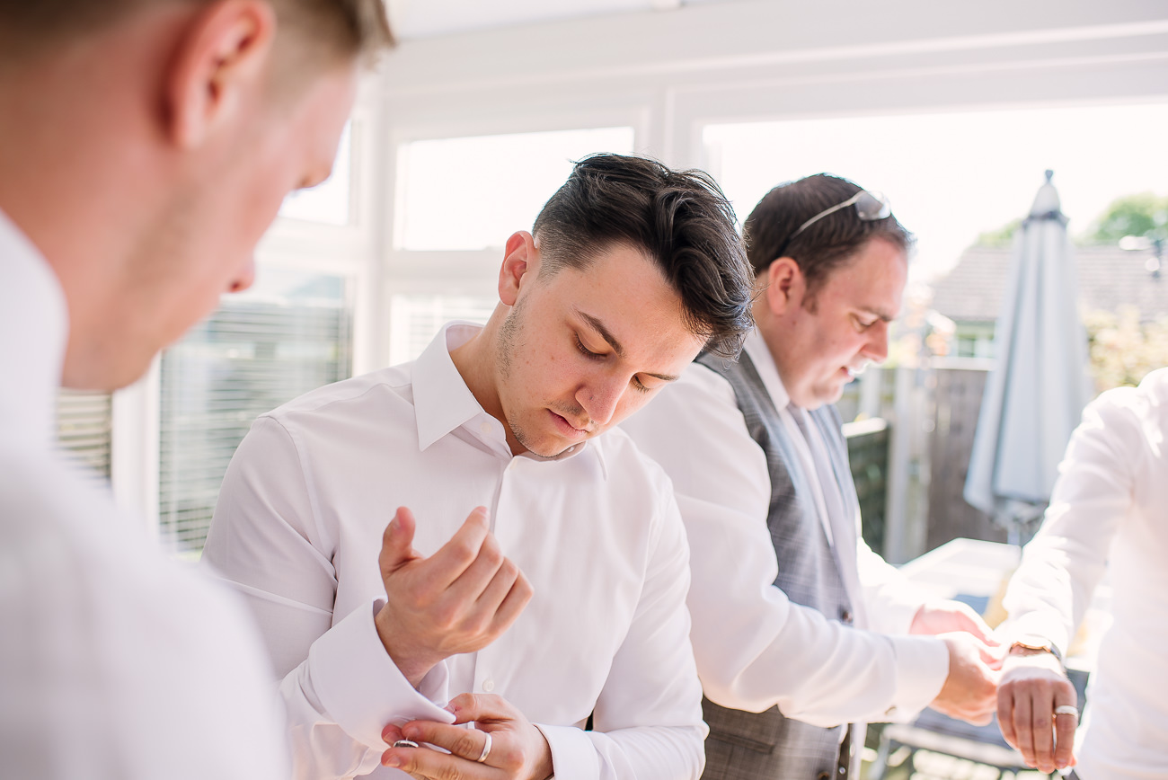 Guys arranging their shirt sleeves during wedding preparations at Russets