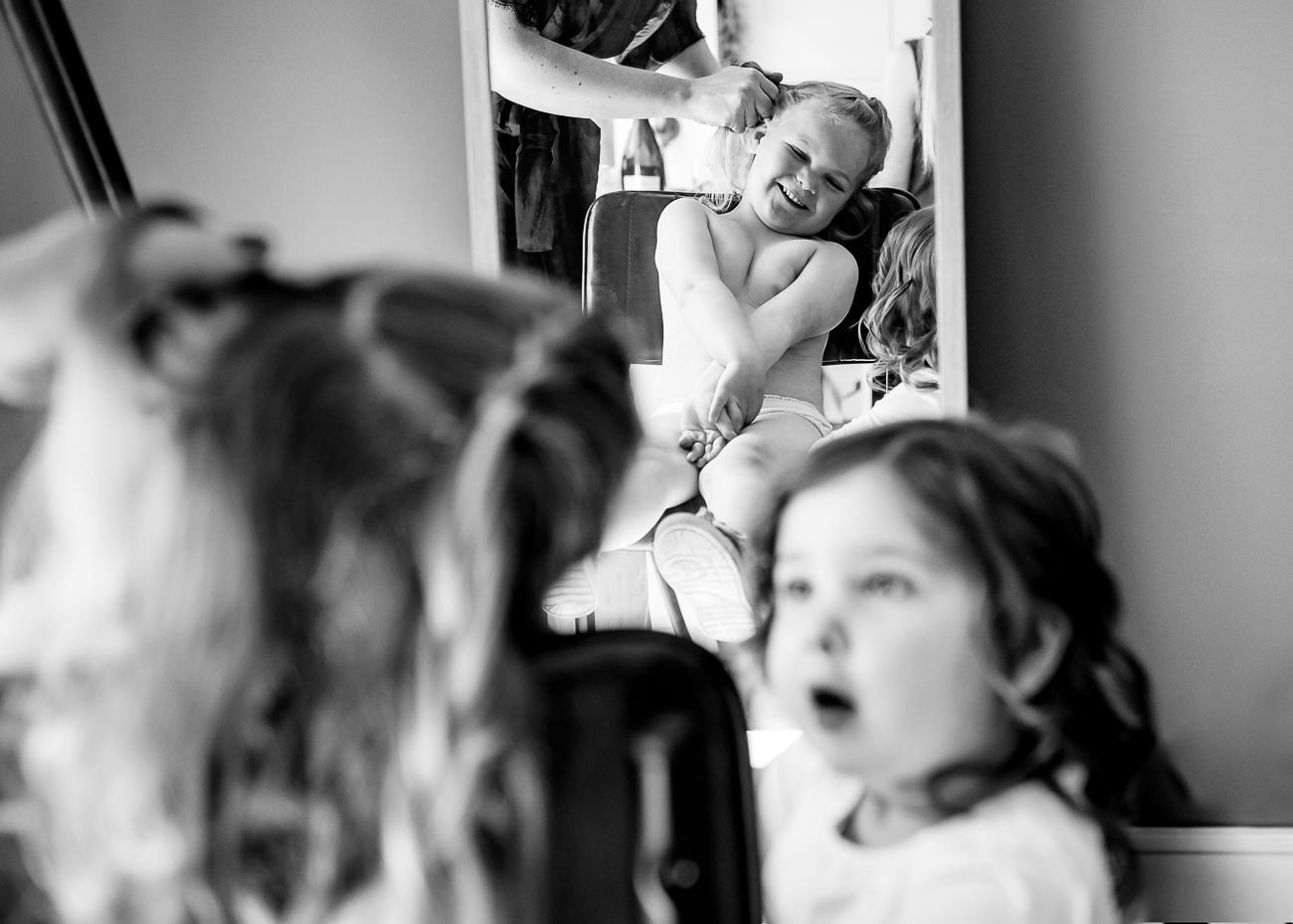 Flower girls having hair done, one looking amazed