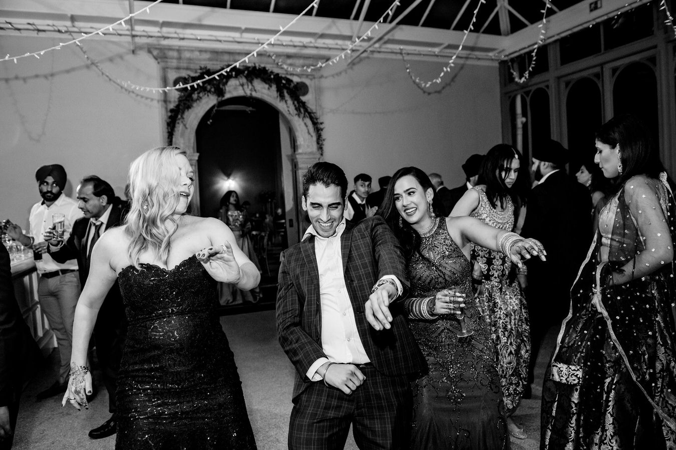 Bride with a glass of champagne in hand is dancing along with her wedding guests.