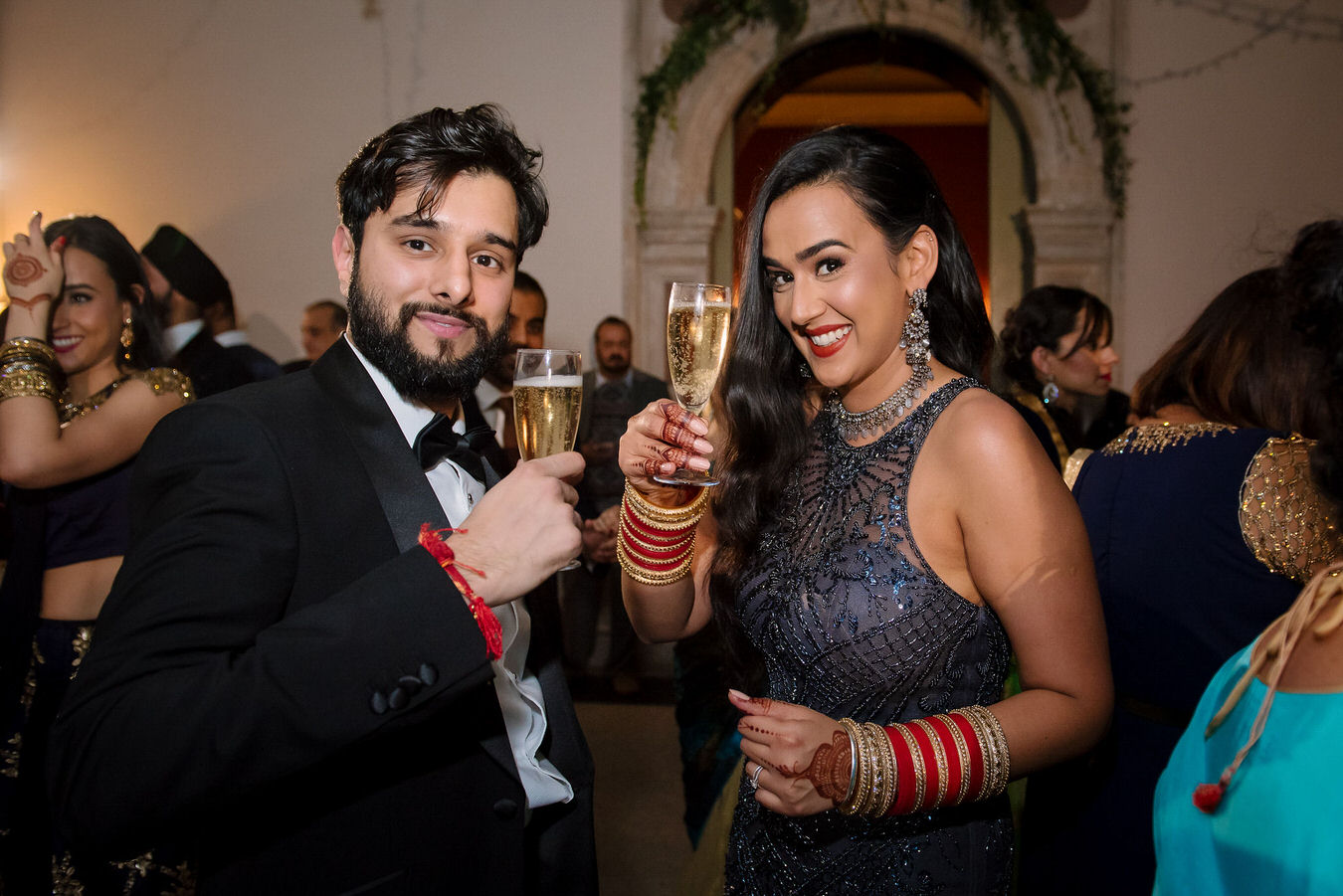 Bride and groom holding the champagne glasses up and putting a smile for their London wedding photographer.