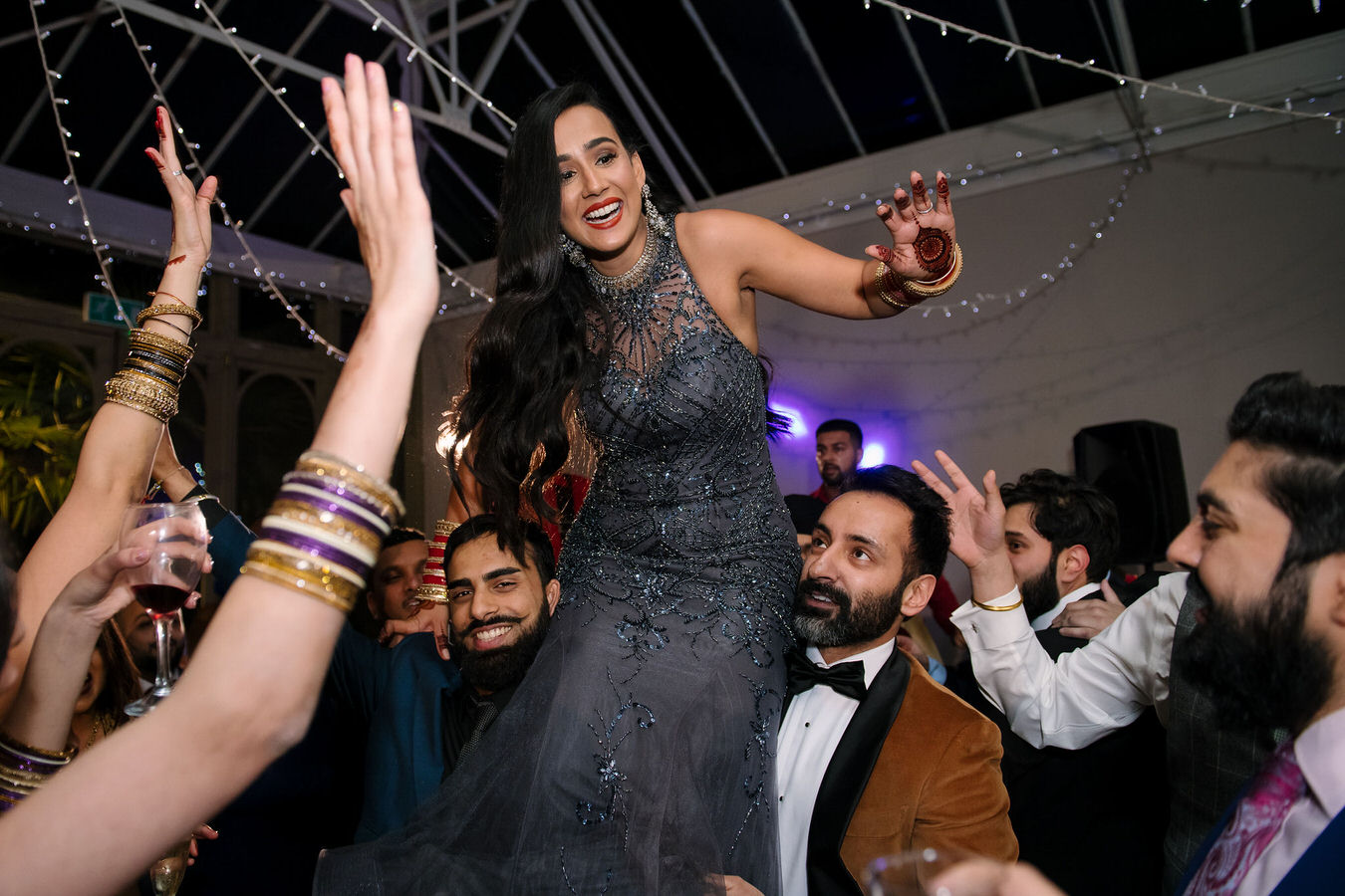 Bride is dancing up on guests shoulders at the wedding reception