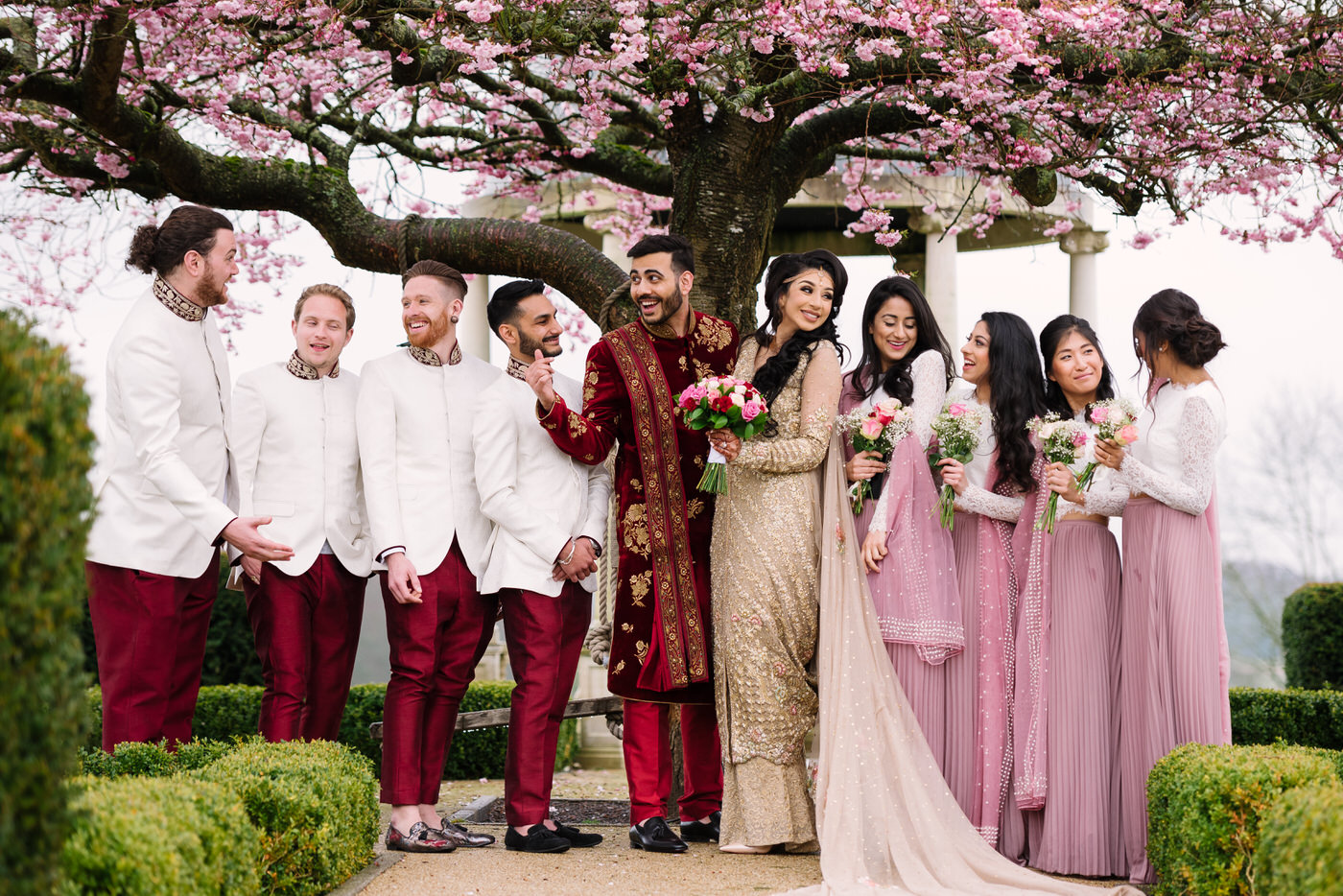 Asian Wedding Photography with bride and groom, groomsmen and bridesmaids under cherry blossom at Froyle Park Surrey