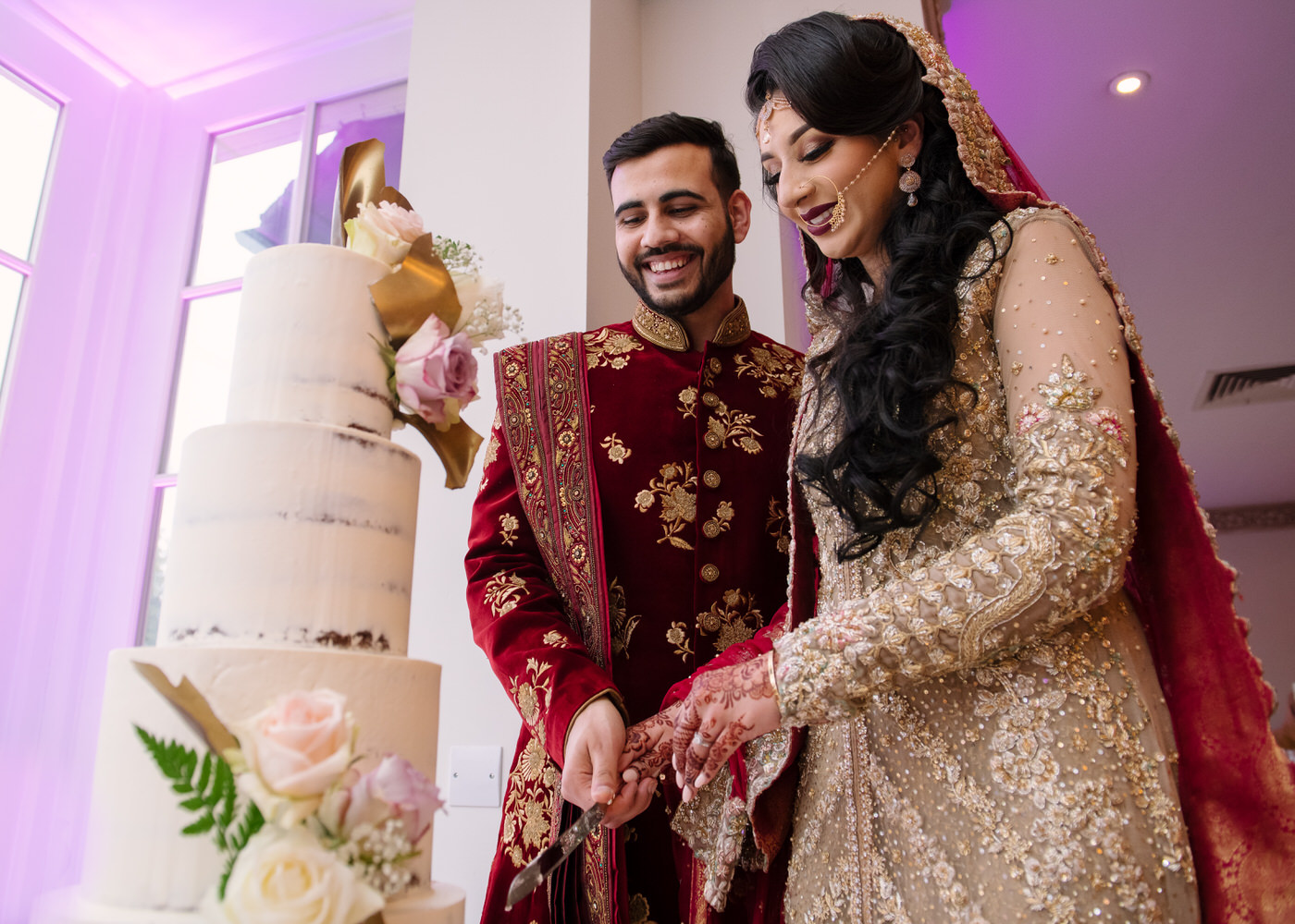 Wedding photography with bride and groom both cutting the cake