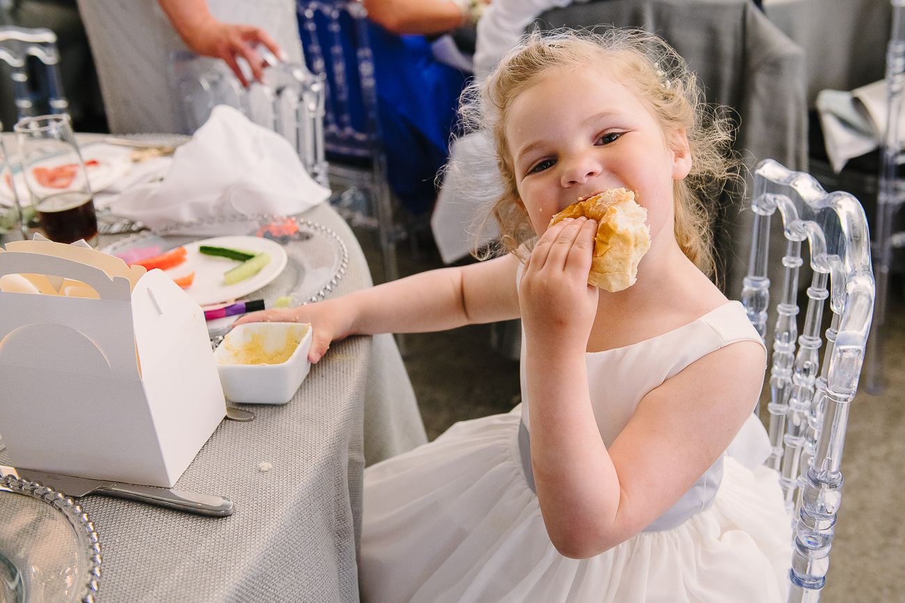Cheeky flower girl in white dress eating bread at Russets Country House