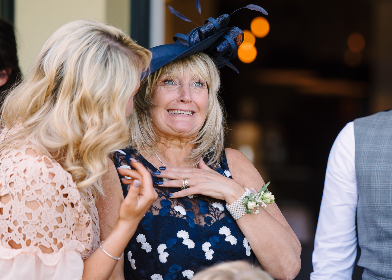 Mother of the groom pulling a face after a guest whispered something in her ear
