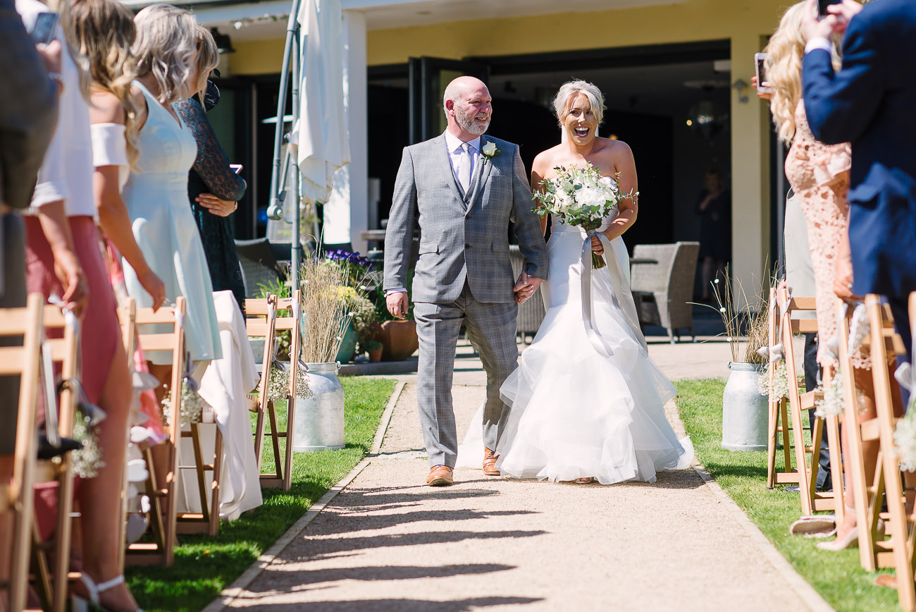 Happy bride walking down the isle with dad during outdoor ceremony at Russets