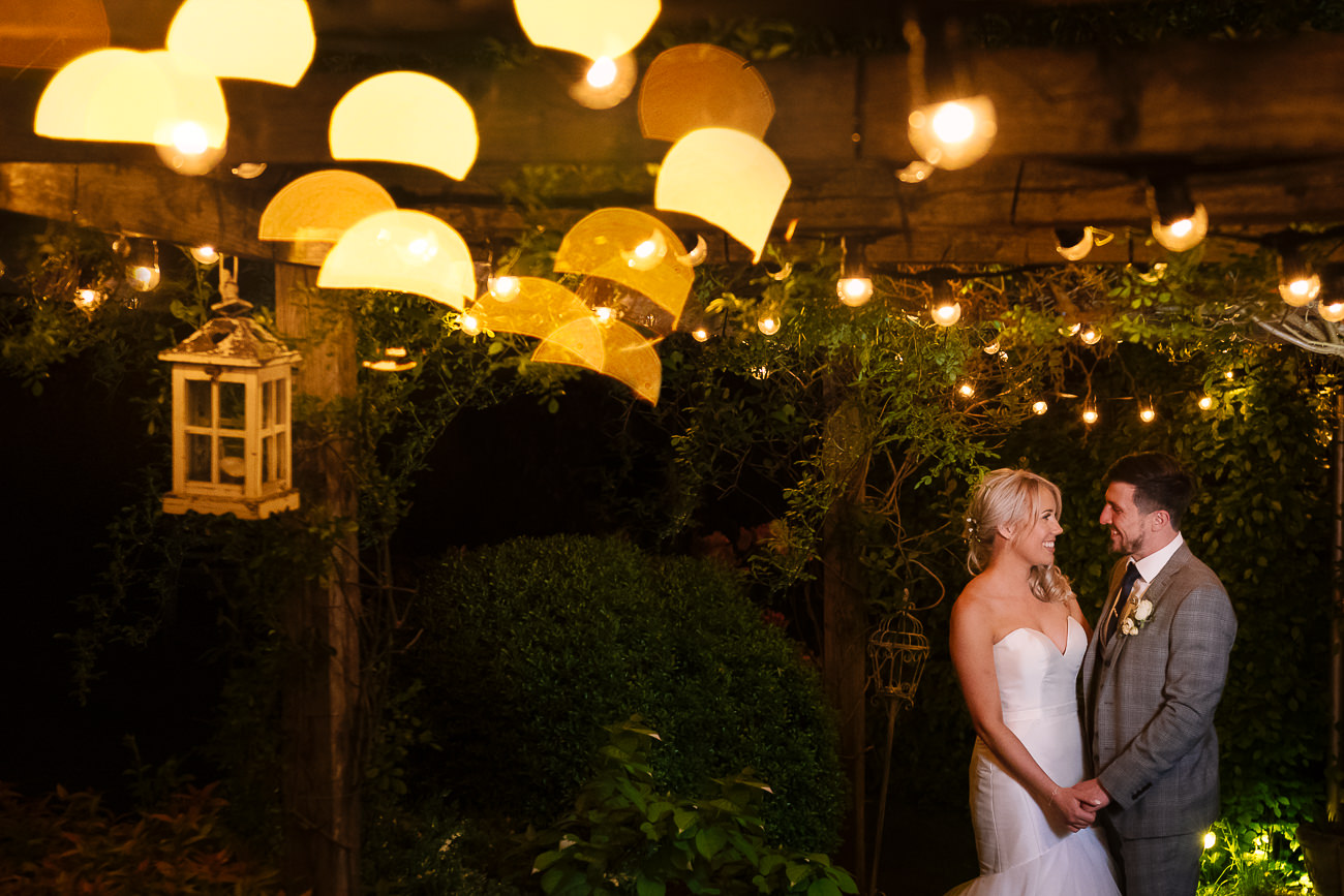 Bride and groom holding hands in the evening under the festoon lights at Russets Country House