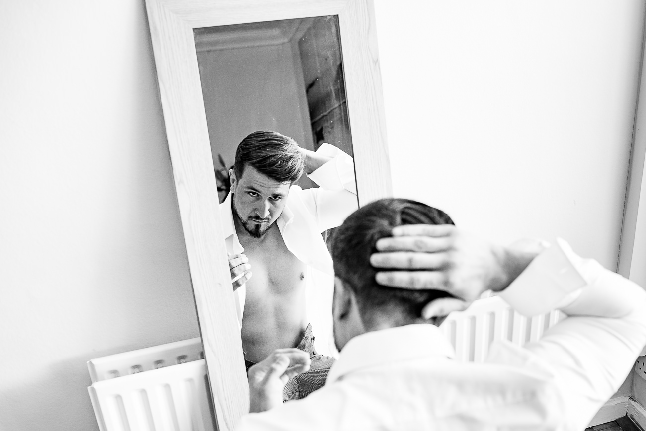 Groom doing his hair done in front of a mirror 