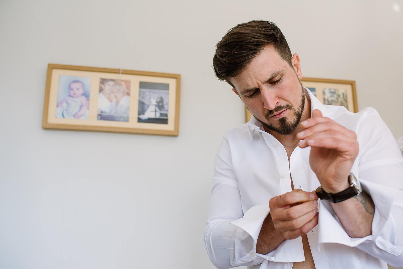 Groom in white shirt puts his wristwatch at preps 