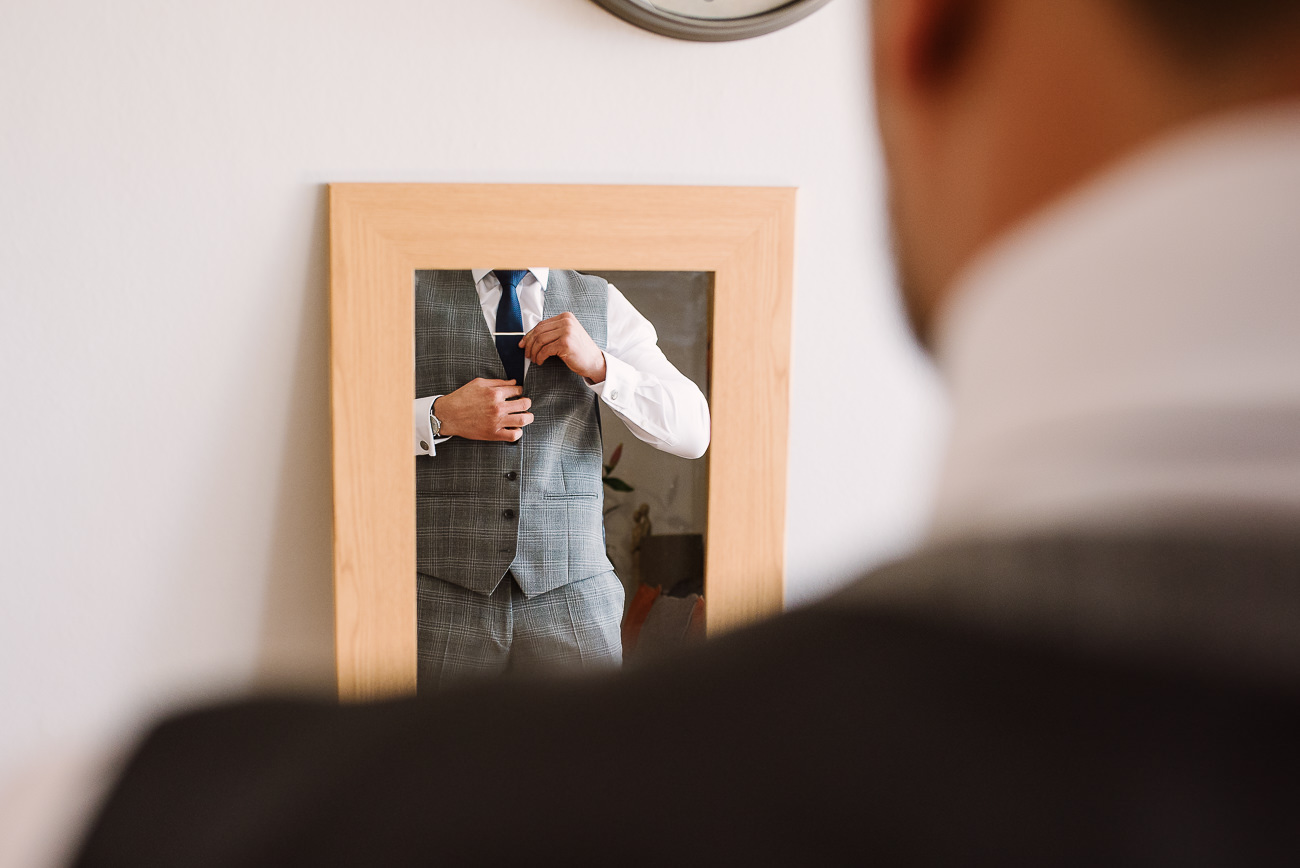 Groom arranges his tie in the mirror