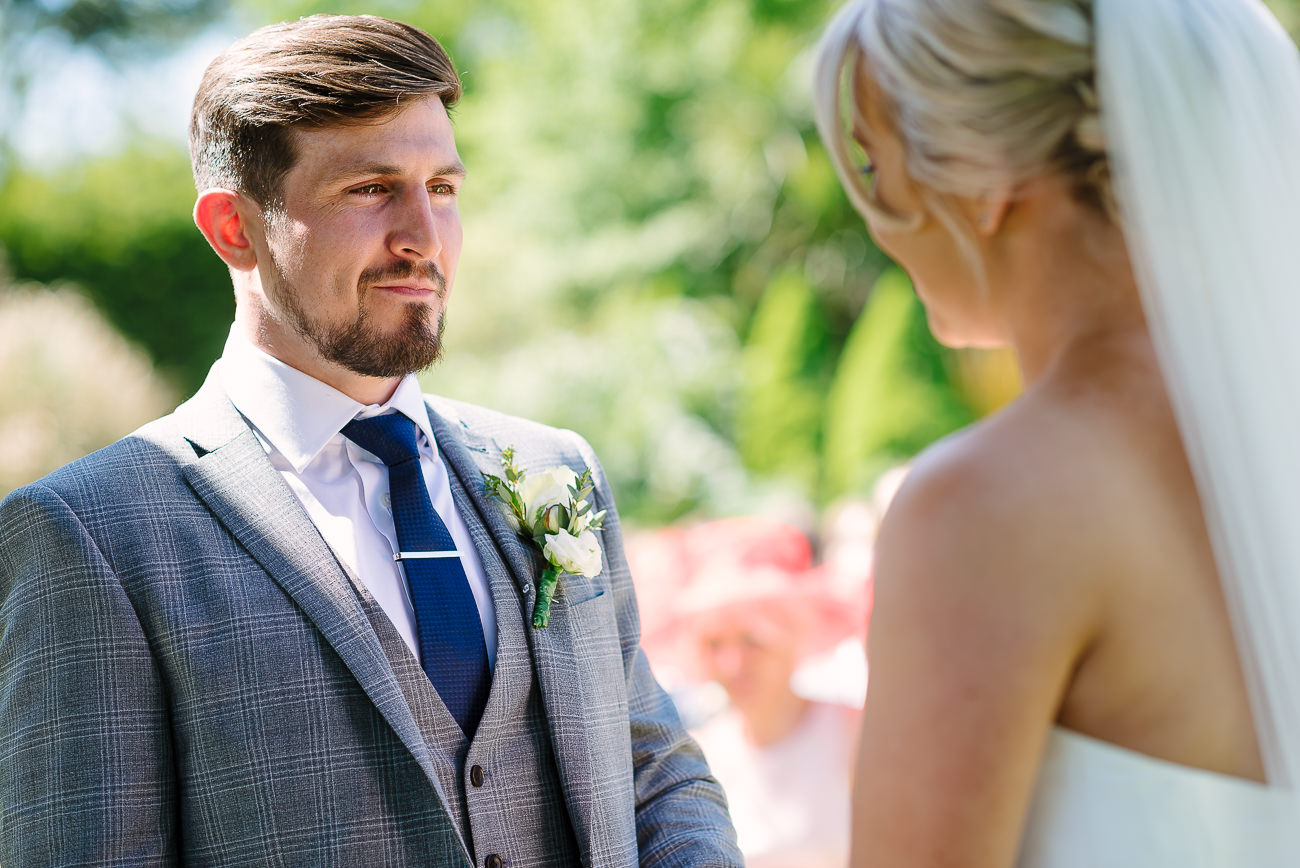 Groom and bride are smiling to each other during ceremony