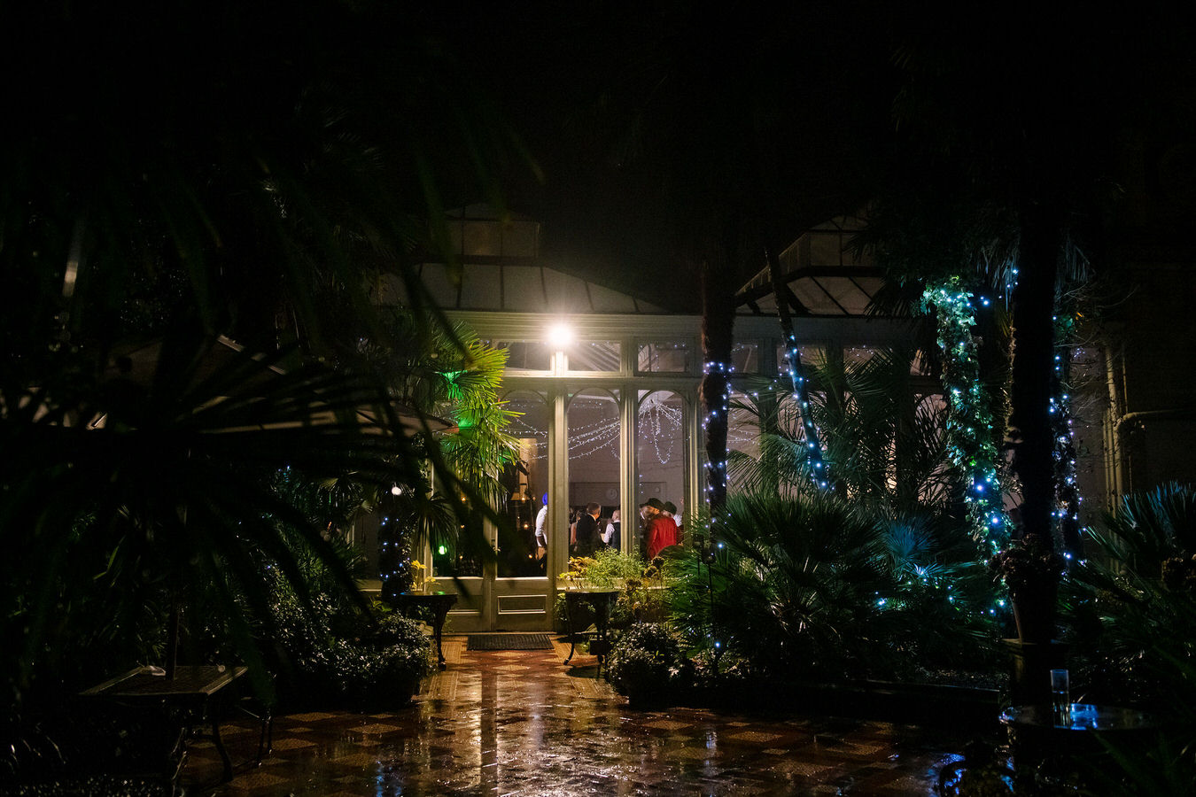 Photography view of the dancefloor at Hampton Court House taken from outside with the green vegetation and blue light fairy lights.