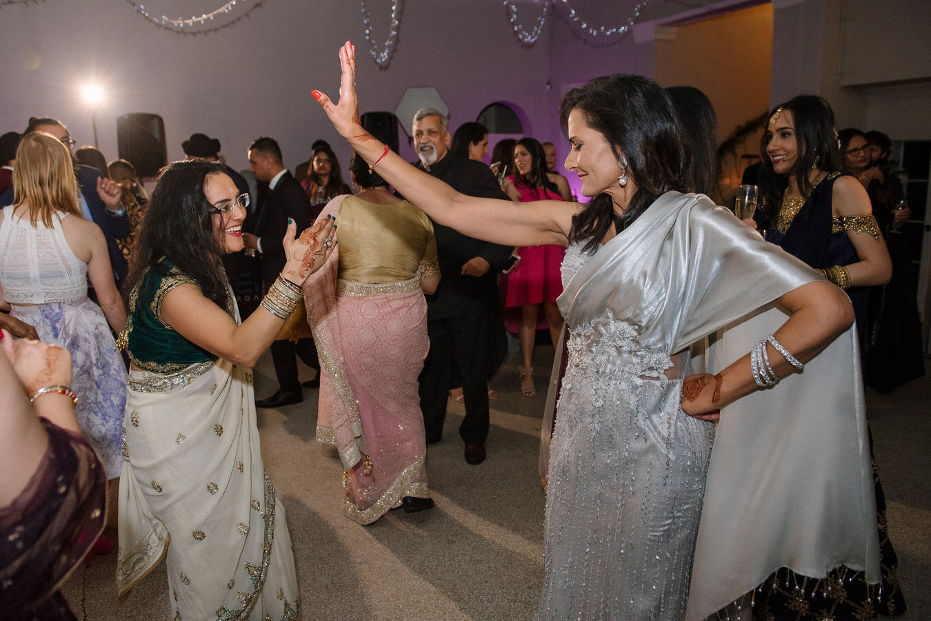 Two female guests are dancing face to face among other guests at Hampton Court House.