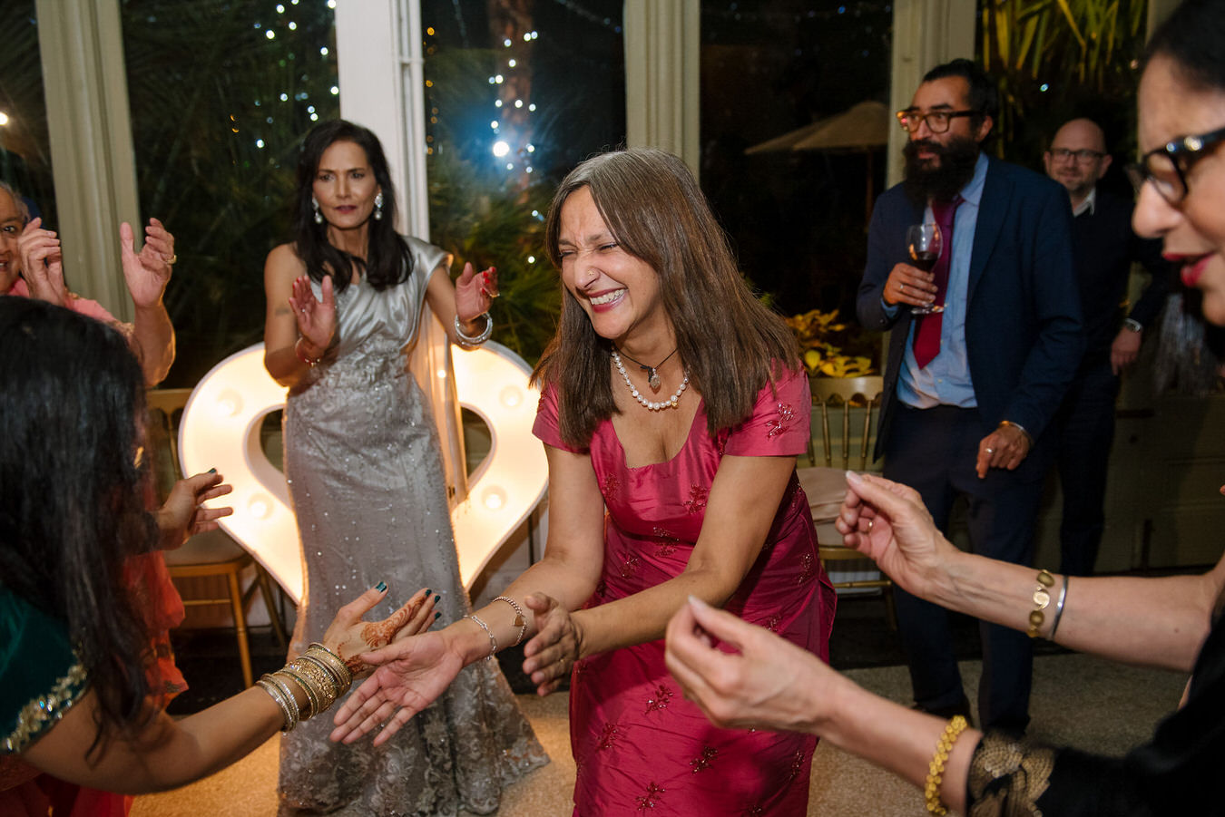 Wedding guests are clapping hands in the rhythm of the Asian music and dance.
