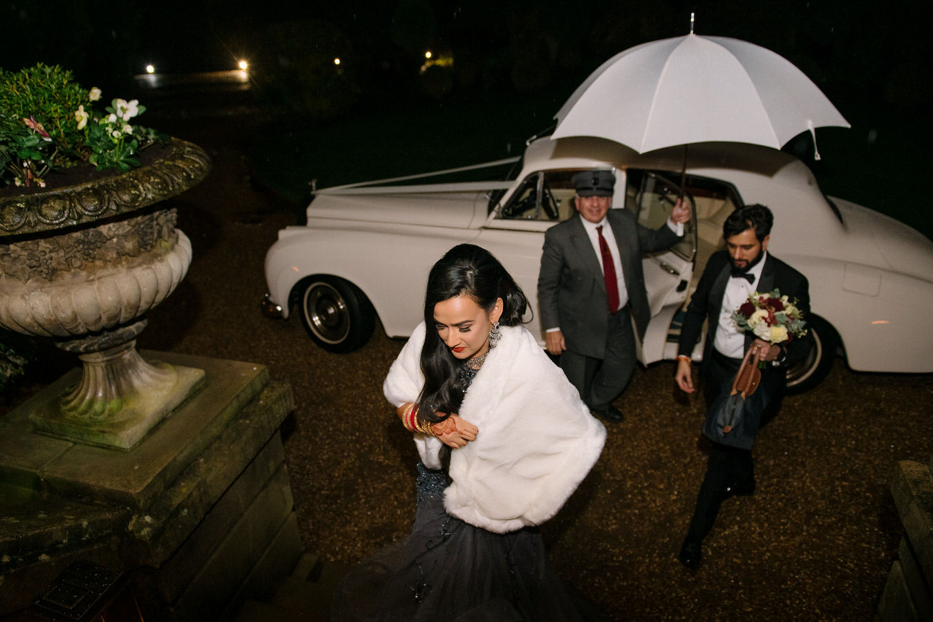 Bride and groom stepping out of a white limo and entering their wedding reception Hampton Court House.