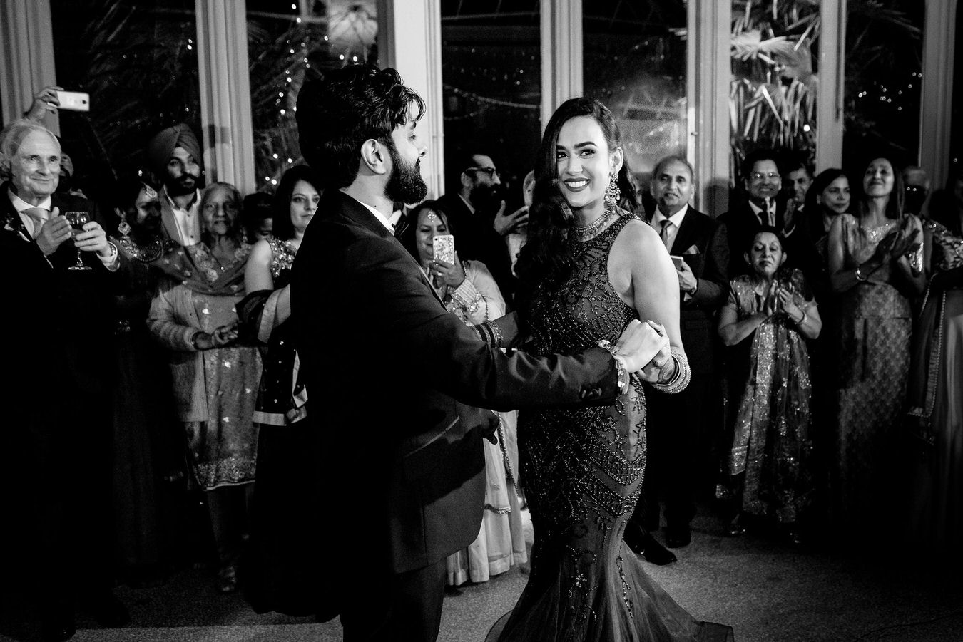 Bride and groom dancing face to face in front of the wedding guests during their first dance at Hampton Court House