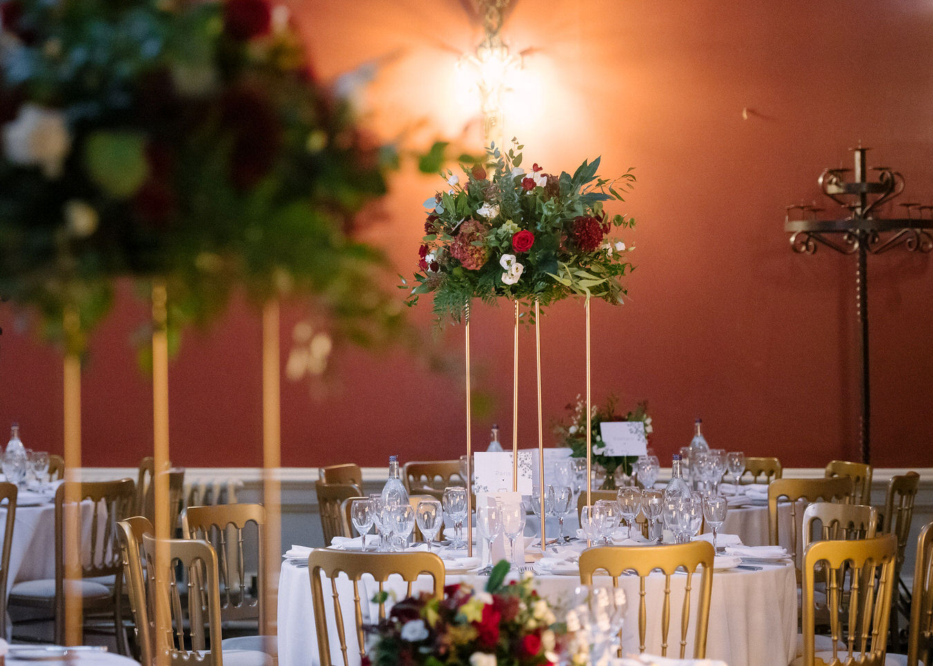 Asian wedding tall table centerpiece with dark red & white flowers at Hampton Court House reception