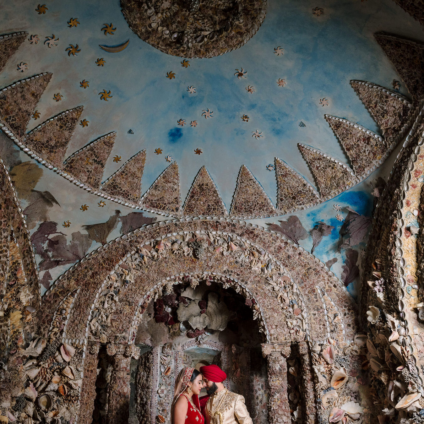 Sikh Asian wedding photographs inside the Hampton Court House shell grotto showing a blue sky with stars and moon made out of shells.