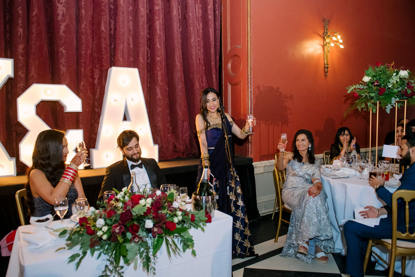 Wedding guests at Hampton Court House are lifting the glasses with champagne at the end of the speech.