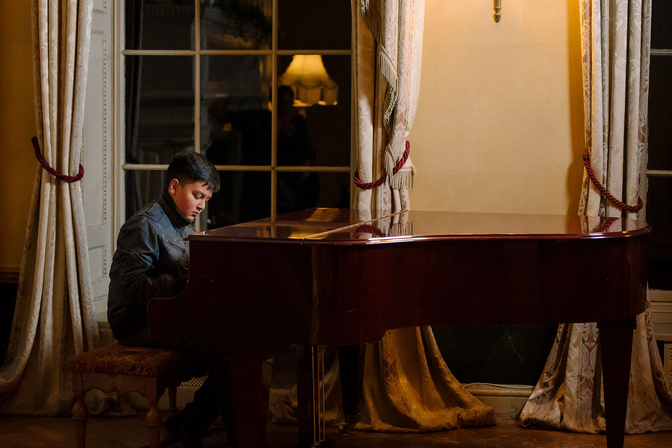 Young boy playing the piano at Hampton Court House